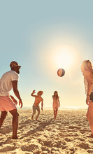 Young Friends Playing With Beach Ball On Sunny Summer Beach