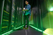 © Rafal Rodzoch/Caia Image - Male IT technician working in dark server room glowing green panels