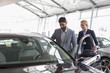 © Martin Barraud/Caia Image - Car saleswoman showing new car to male customer in car dealership showroom