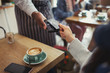 © Caiaimage/Paul Bradbury/Caia Image - Customer credit card paying worker contactless payment in cafe