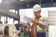 © Lukasz Olek/Caia Image - Male foreman reviewing paperwork on clipboard in factory