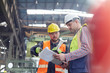 © Lukasz Olek/Caia Image - Male foreman and worker with clipboard talking in factory