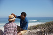© Sam Edwards/Caia Image - Smiling man placing hat on girlfriend on sunny summer ocean beach