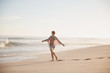 © Sam Edwards/Caia Image - Carefree woman walking arms outstretched on sunny summer ocean beach
