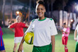© Sam Edwards/Caia Image - Portrait smiling, confident young female soccer player ball on field at night