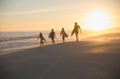 © Sam Edwards/Caia Image - Silhouette family surfers walking surfboards on sunny summer sunset beach