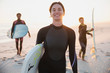 © Sam Edwards/Caia Image - Portrait smiling female surfer in wet suit carrying surfboard family on sunny summer beach