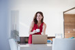 © Sam Edwards/Caia Image - Smiling brunette woman drinking coffee, working at laptop at dining room table