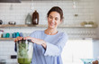 © Sam Edwards/Caia Image - Smiling woman making healthy green smoothie in blender in kitchen