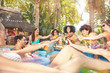 © Trevor Adeline/Caia Image - Enthusiastic friends drinking, toasting beer bottles and cocktails at summer swimming pool party