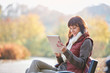 © Agnieszka Wozniak/Caia Image - Woman using digital tablet on sunny autumn park bench
