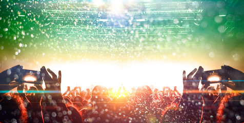 concert stage shot from inside a concert hall with many people silhouettes attending the show, clapp