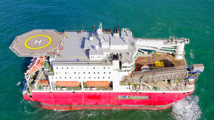 Large Platform supply ship with Helipad and two large cranes, anchored at Sea, Aerial view.