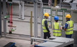 © Martin Barraud/Caia Image - Supervisor and workers reviewing information on wall in factory
