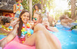 © Trevor Adeline/Caia Image - Portrait enthusiastic, laughing young women friends drinking and playing in summer swimming pool