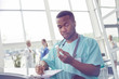 © Rafal Rodzoch/Caia Image - Male nurse with clipboard checking medicine bottle in hospital lobby