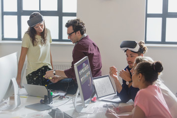Computer programmers programming virtual reality simulator glasses in office