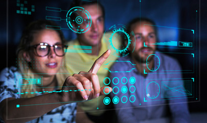 Computer programmers examining data on futuristic hologram