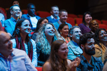 Smiling, Enthusiastic Audience In Dark Auditorium