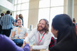 © Sam Edwards/Caia Image - Smiling businessman shaking hands with colleague at conference