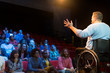 © Martin Barraud/Caia Image - Speaker in wheelchair on stage talking to conference audience