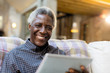 © Sam Edwards/Caia Image - Portrait smiling, confident senior man using digital tablet on sofa