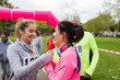 © Sam Edwards/Caia Image - Daughter placing medal around neck of mother at charity run in park
