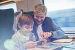 © Agnieszka Olek/Caia Image - Father and son using smart phone on passenger train