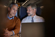 © Agnieszka Olek/Caia Image - Businessmen talking, working at laptop on passenger train at night