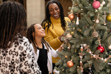 Smiling Daughter Decorating Christmas Tree With Mother