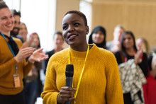 Smiling Businesswoman Speaker With Microphone At Conference