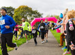 © Chris Ryan/Caia Image - Runners reaching for water, running at charity run in park