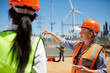 © Trevor Adeline/Caia Image - Female engineer digital tablet talking to colleague at wind turbine power plant