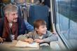 © Agnieszka Olek/Caia Image - Father and son looking out window on passenger train