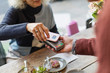 © Tom Merton/Caia Image - Woman with smart phone using contactless payment at cafe