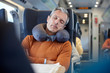 © Agnieszka Olek/Caia Image - Tired businessman with neck pillow sleeping on passenger train