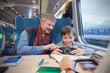 © Agnieszka Olek/Caia Image - Father and son using smart phone on passenger train