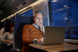 © Agnieszka Olek/Caia Image - Focused businessman working at laptop on passenger train at night
