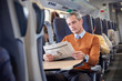 © Rafal Rodzoch/Caia Image - Businessman reading newspaper on passenger train