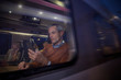 © Rafal Rodzoch/Caia Image - Businessman using smart phone at window on passenger train at night