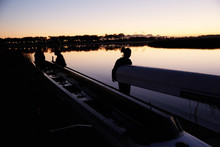 Female Rowing Team Carrying Scull At Sunrise Lake