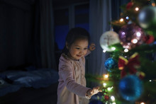 Curious, Cute Girl Touching Illuminated Christmas Tree
