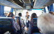 © Trevor Adeline/Caia Image - Female tour guide with microphone talking to active senior tourists on tour bus