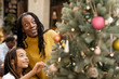 © Sam Edwards/Caia Image - Mother and daughter decorating Christmas tree