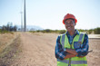 © Trevor Adeline/Caia Image - Portrait smiling engineer on dirt road at wind turbine power plant