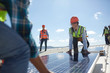 © Trevor Adeline/Caia Image - Engineers lifting solar panel at sunny power plant