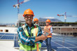 © Trevor Adeline/Caia Image - Portrait confident engineer installing solar panels on sunny rooftop