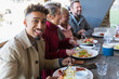 © Chris Ryan/Caia Image - Portrait smiling young man eating breakfast with friends at restaurant outdoor patio