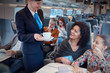 © Agnieszka Olek/Caia Image - Attendant serving coffee to mother with daughter on passenger train