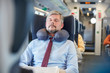 © Agnieszka Olek/Caia Image - Tired businessman with neck pillow sleeping on passenger train